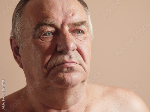 Aged man portrait on light background.