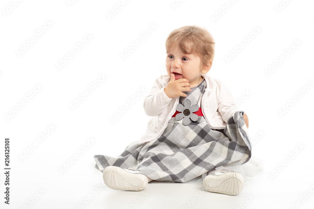 Elegant baby girl 1 year old sitting on the studio floor. White Background. Elegant baby girl 1 year old sitting on the studio floor. White Background.