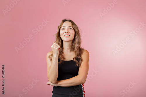 Portrait of young cheerful blonde woman wearing black dress against pink background © Leika production