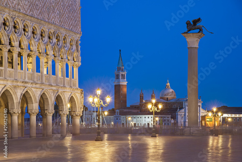 Venice night city view of Square Piazza San Marco, Doge's Palace, column of winged Lion, gondolas wharf and San Giorgio Maggiore island with basilica and campanile in light of streetlights © EMrpize
