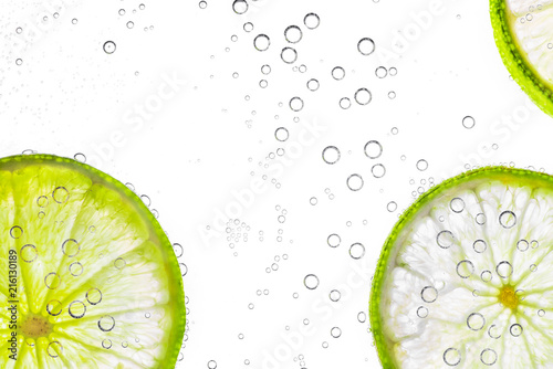 close up fresh lime sliced in soda or water bubbles, isolated on white background