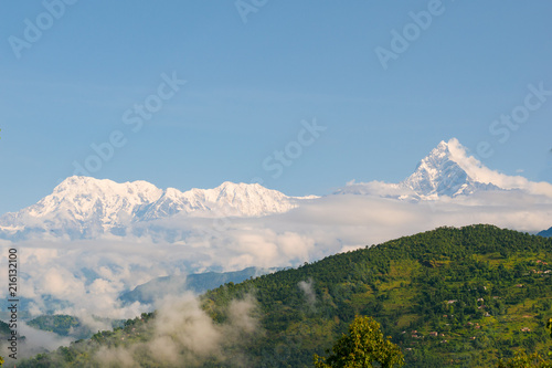 Annapurna mountain range in the Himalayas in a sea of clouds, over green hills, near Pokhara, Nepal