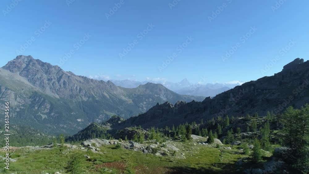 moving backward above clear blue lake and pine woods in sunny summer day.Europe Italy Alps Valle d'Aosta outdoor green nature scape mountains wild aerial establisher.4k drone flight establishing shot moving backward above clear blue lake and pine woods in sunny summer day.Europe Italy Alps Valle d'Aosta outdoor green nature scape mountains wild aerial establisher.4k drone flight establishing shot