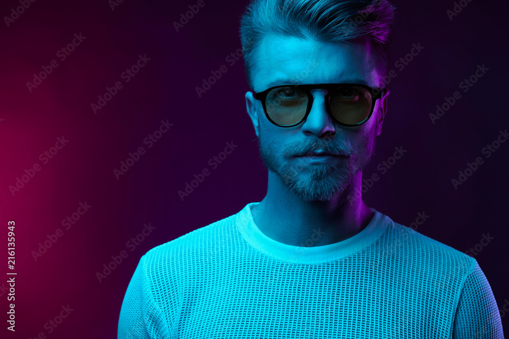Neon light studio portrait of serious man model with mustaches and beard in sunglasses and white t-shirt Neon light studio portrait of serious man model with mustaches and beard in sunglasses and white t-shirt