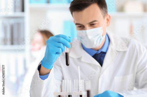 Scientist holding test tube with sample in laboratory