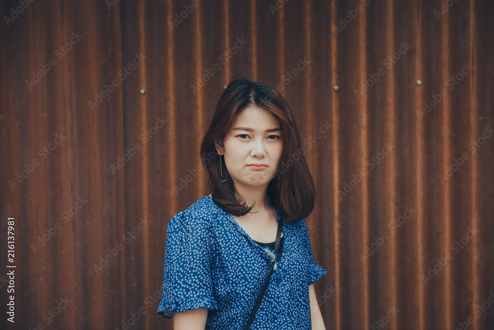 Portrait of angry young woman standing with blue blouse on old background Portrait of angry young woman standing with blue blouse on old background