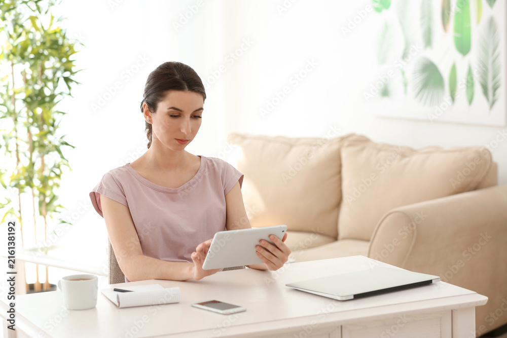 Young female freelancer working with tablet computer at home