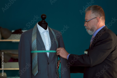 Mature tailor taking measur...
