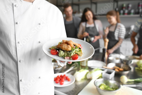 Male chef holding plate wit...