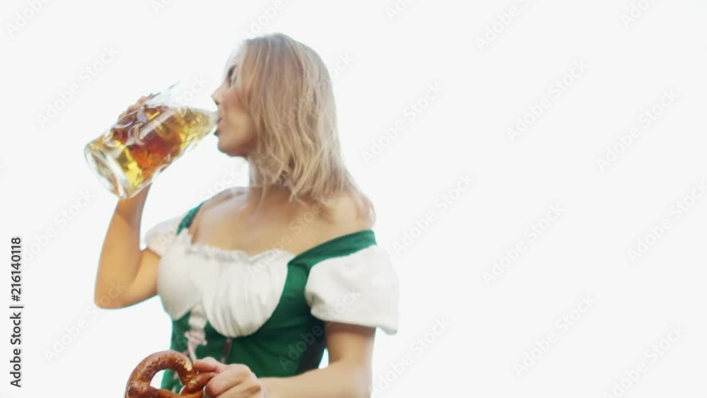 Girl in traditional Bavarian Tracht drinking beer out of a huge mug, holding pretzel in other hand Girl in traditional Bavarian Tracht drinking beer out of a huge mug, holding pretzel in other hand