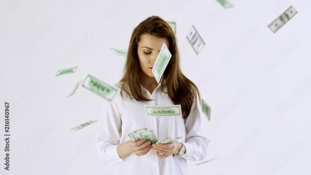 Slowmo studio shot of confident businesswoman in shirt standing isolated on white background and counting cash as money falling on her from above Slowmo studio shot of confident businesswoman in shirt standing isolated on white background and counting cash as money falling on her from above