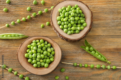 Bowls with delicious fresh green peas on wooden table