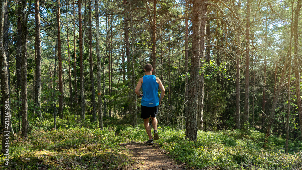 Man running along a trail in a forest, outdoor trailrunning Man running along a trail in a forest, outdoor trailrunning