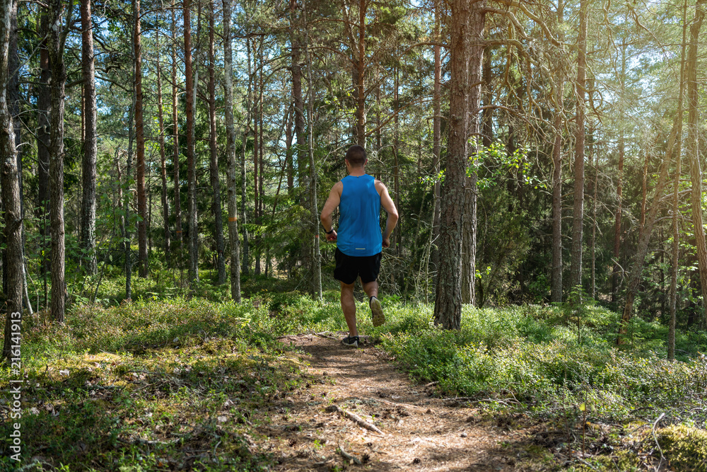 Man running along a trail in a forest, outdoor trailrunning Man running along a trail in a forest, outdoor trailrunning