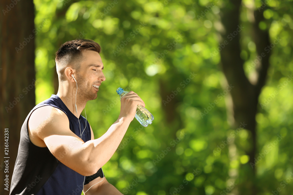 Sporty man drinking water in park Sporty man drinking water in park