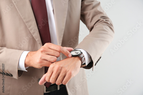 Businessman looking at his watch on light background, closeup. Time management concept