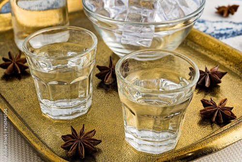 Glasses and bottle of traditional drink Ouzo or Raki on bronze dish with anise star seeds