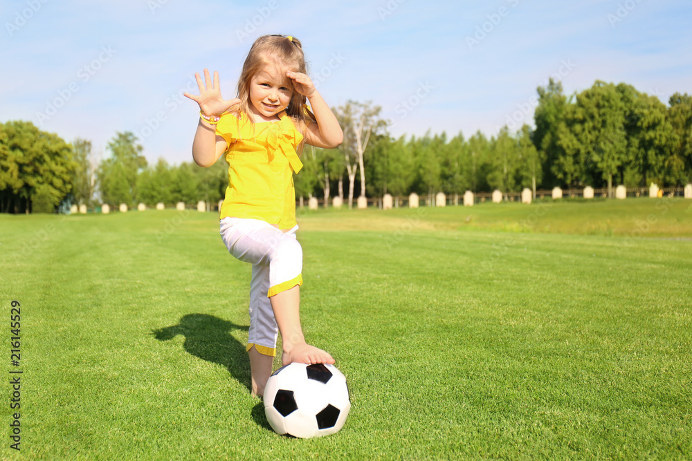 Cute little girl playing football in park on sunny day Cute little girl playing football in park on sunny day