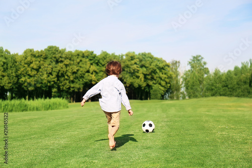 Cute little boy playing football in park on sunny day
