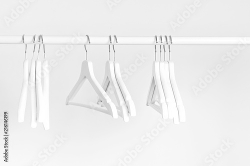 Many wooden white hangers on a rod, isolated on white wall background. Store concept, sale, design, empty hanger. Place for text.