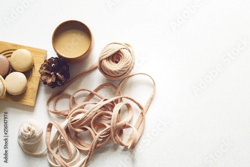 Coffee, four macarons and spruce cone and a tangle on the white table. Sunny day. Flat lay with copy space for text.