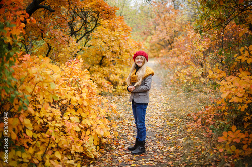 portrait of pretty and happy girl in a red beret walking in beautiful autumn park © AnnKot