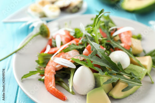 Tasty salad with avocado, quail eggs and shrimps on plate, closeup