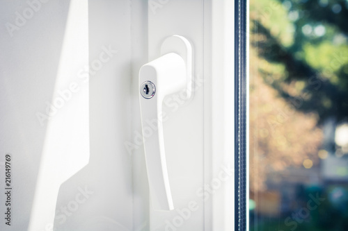 Macro Of A Lockable Window Handle Of A Closed White Window With Trees In Background