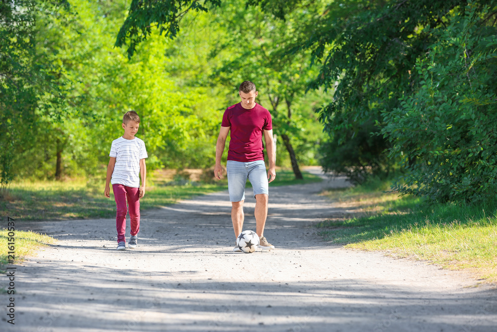 Little boy with his dad playing football outdoors Little boy with his dad playing football outdoors