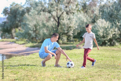 Father with son playing football outdoors © Pixel-Shot