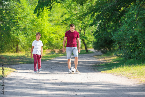 Little boy with his dad playing football outdoors