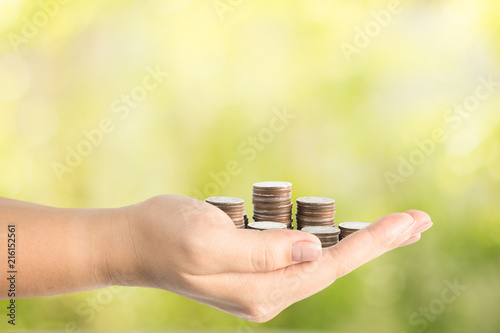 Hand carrying coins with nature background.