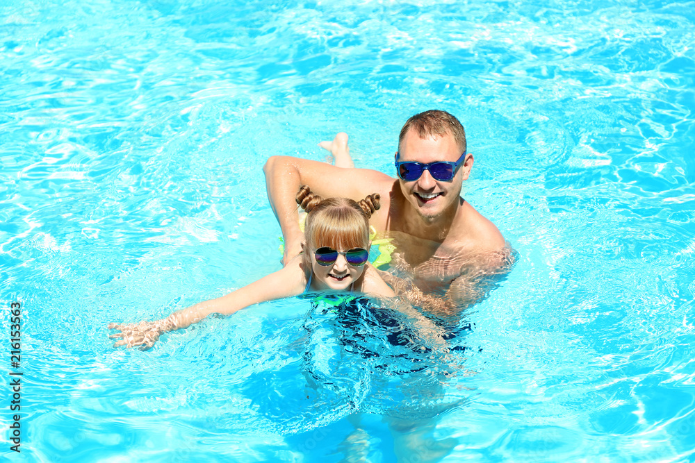 Happy father with daughter playing in swimming pool