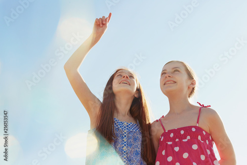 Best friends pointing up and looking up at sky photo