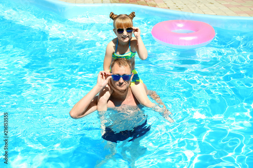 Happy father with daughter resting in swimming pool