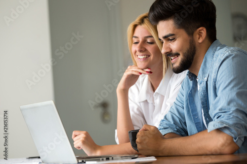 Beautiful young couple is using a laptop and smiling