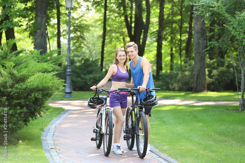 Sporty young couple with bicycles in park
