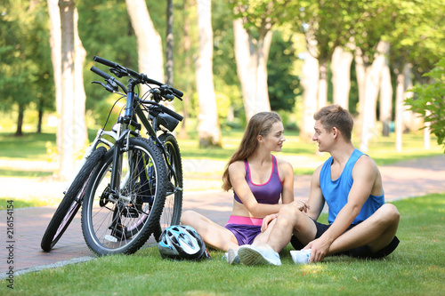 Young couple resting after riding bicycles in park