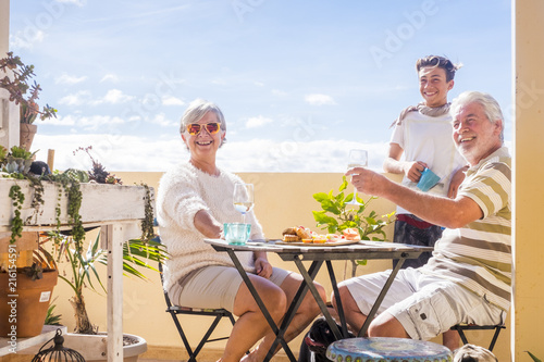 grandfathers adult mature and teenager nephew enjoy outdoor in the terrace some leisure with food and drinks. ocean and city view, vacation sunny day nice weather concept and background. happy people photo