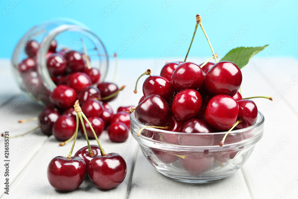 bowl and bottle with ripe cherries on the table bowl and bottle with ripe cherries on the table