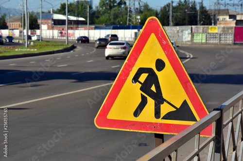 Temporary signal road sign REPAIR WORKS on a city street against traffic