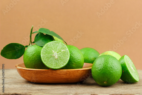 Fresh limes in wooden bowl on wooden background