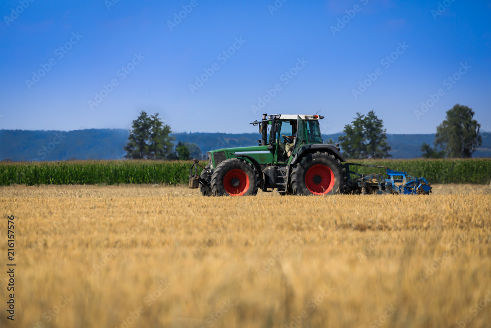 Traktor auf dem Feld bei der Arbeit, Sommerwetter Traktor auf dem Feld bei der Arbeit, Sommerwetter