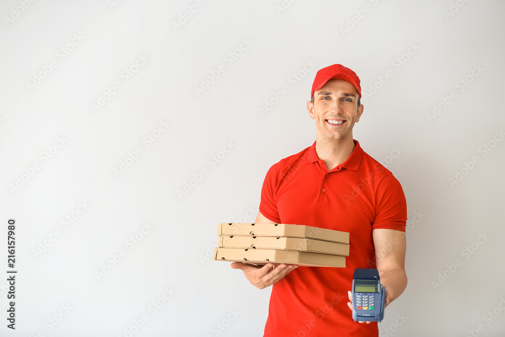 Young man with pizza boxes and bank terminal on light background. Food delivery service Young man with pizza boxes and bank terminal on light background. Food delivery service