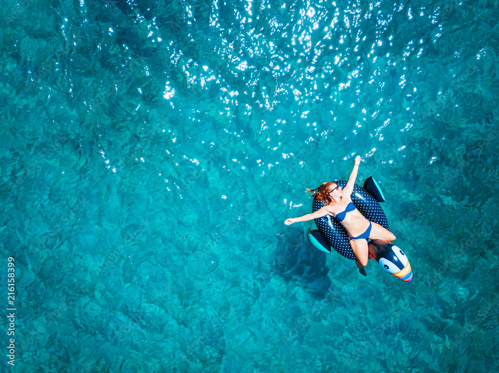 Aerial view of woman floating on the water mattress in the turquoise sea