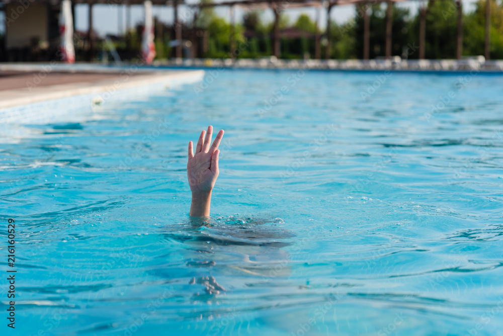 Hand of a drowning person in a swimming pool.