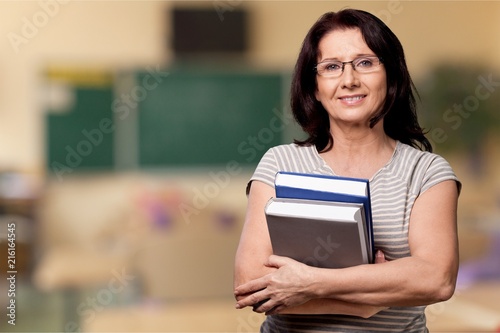 Mature woman teacher with books on background