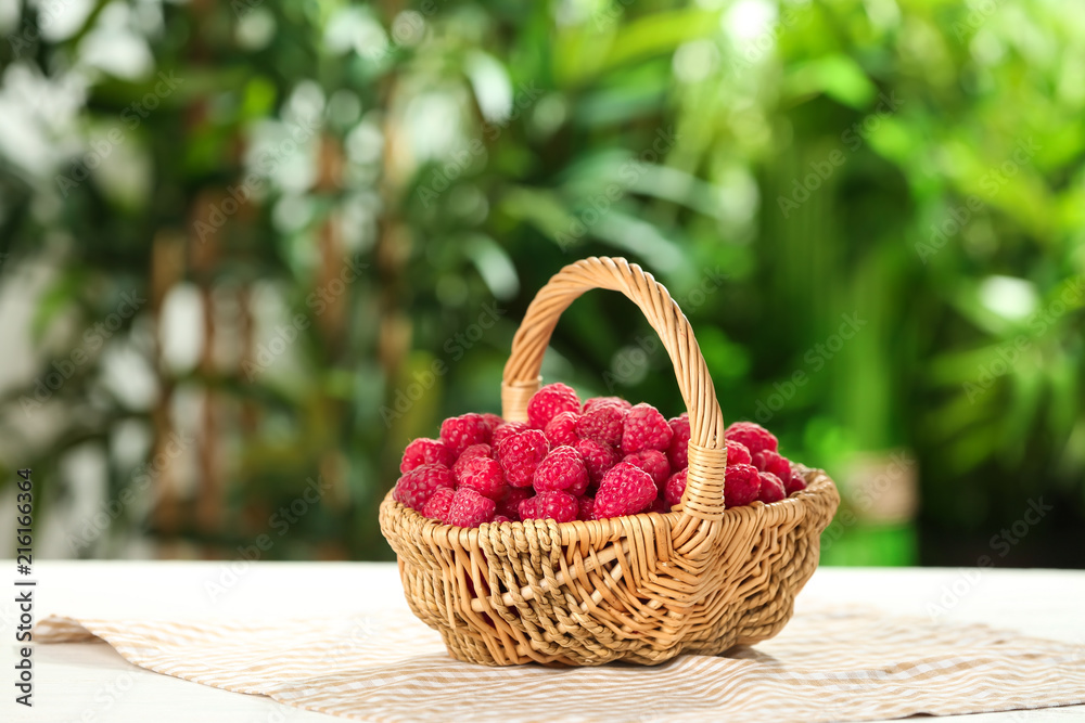 Wicker basket with fresh ripe raspberries on table outdoors Wicker basket with fresh ripe raspberries on table outdoors