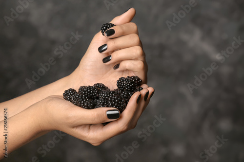 Hands of beautiful young woman with professional manicure holding blackberry on dark grey background