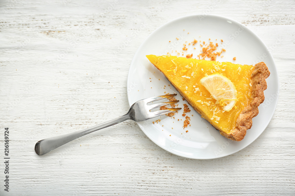 Plate with piece of tasty lemon pie on white wooden table - obrazy, fototapety, plakaty 